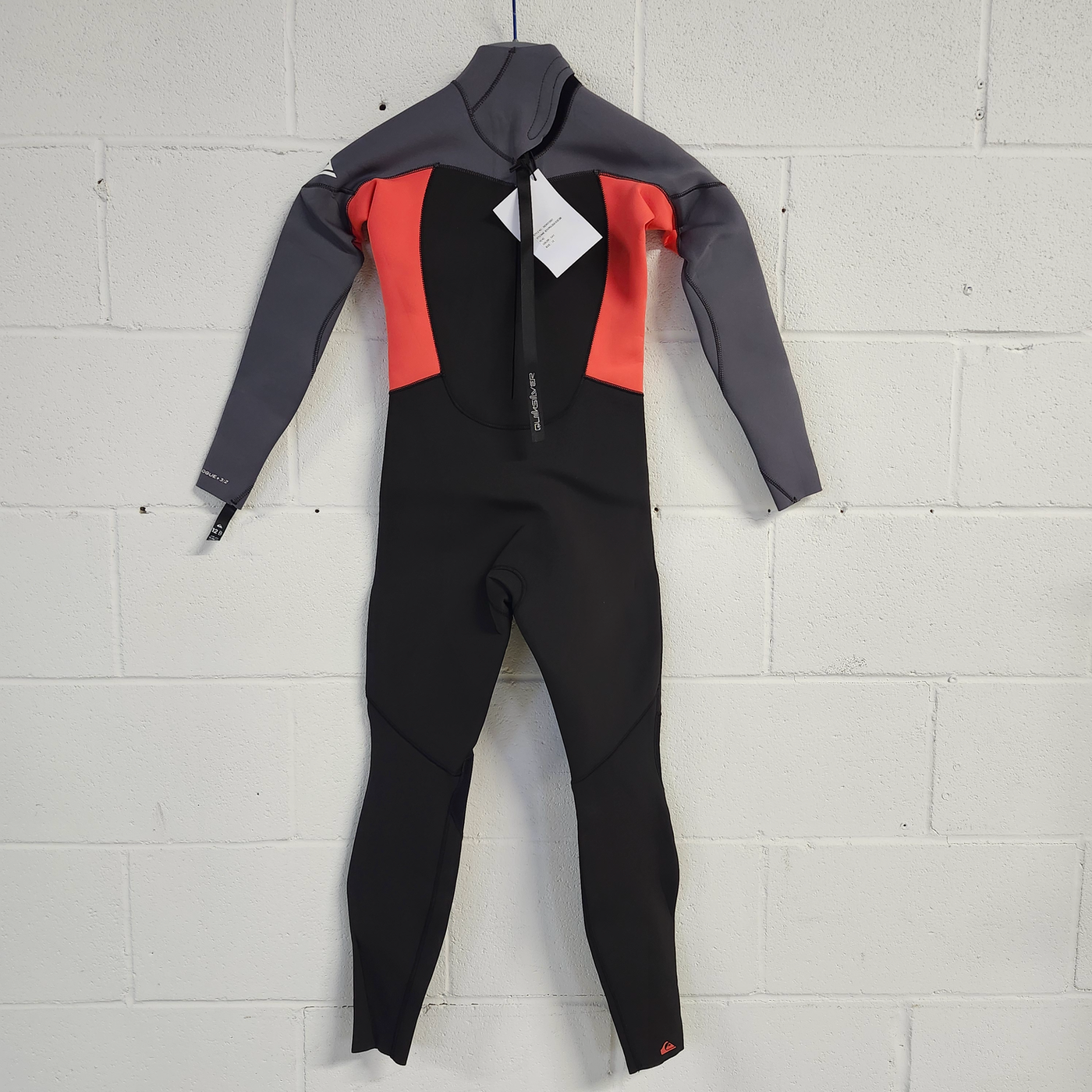 Wetsuit with gray, red, and black sections on a light gray tiled floor.