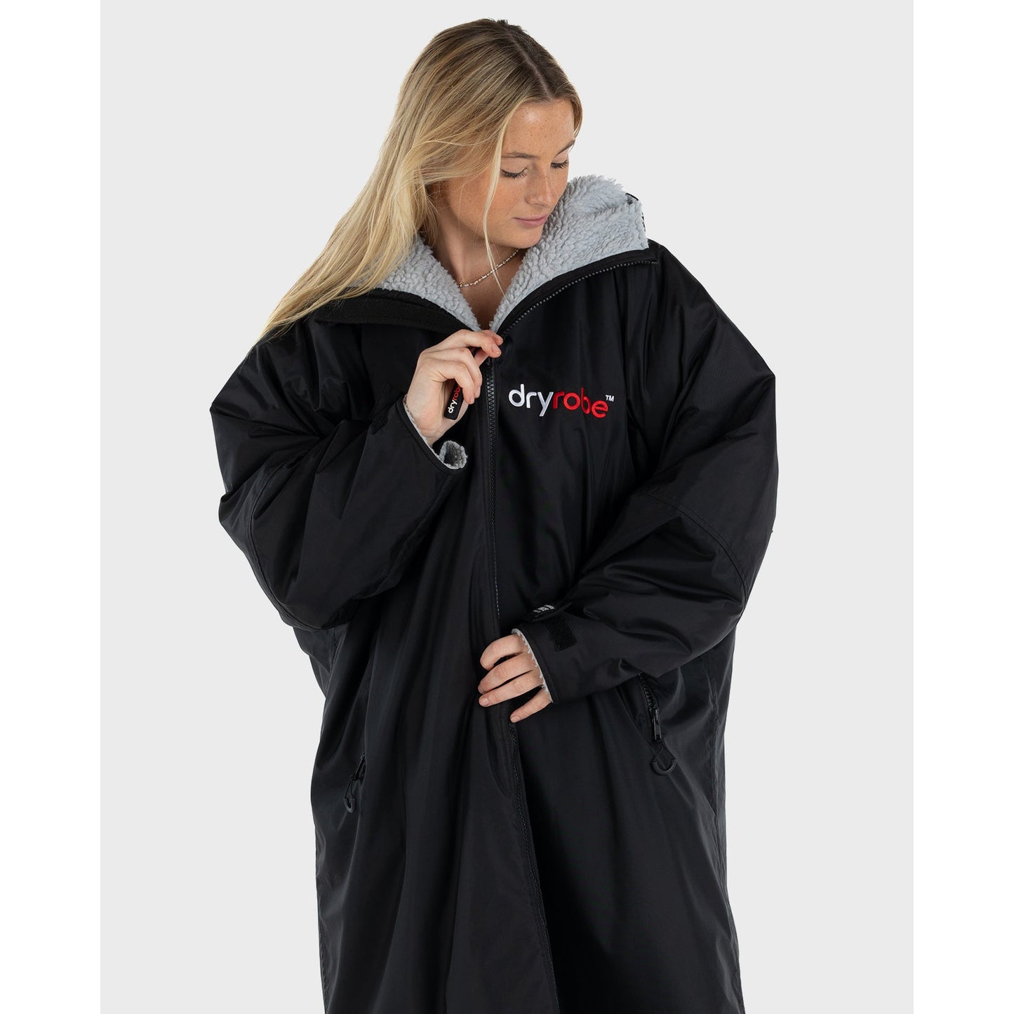Person wearing a black dryrobe with a visible brand logo on a white background